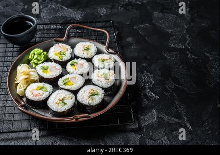 Kimbap gimbap ripieno di verdure, uova, acciughe e granchi, involtino di riso coreano. Sfondo nero. Vista dall'alto. Copia spazio. Foto Stock