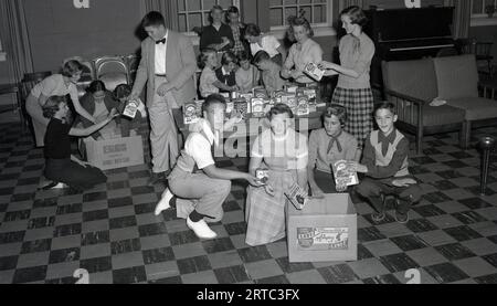 Anni '1950, giovani storici americani che cercano prodotti da forno in casa dell'epoca in un centro giovanile, negli Stati Uniti. I prodotti includono: pillsbury; mix di pancake; mix di hot roll, fiocchi d'avena arricchiti di zia Jemima. Mix di torte Betty Crocker e una scatola vuota di patatine jakes. Foto Stock