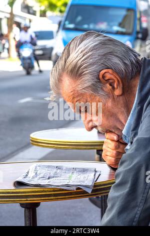 Uomo anziano che studia giornale per suggerimenti sulle scommesse - Tours, Indre-et-Loire (37), Francia. Foto Stock