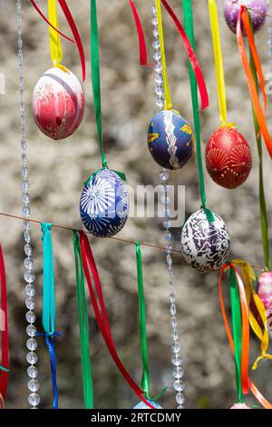 Le uova dipinte pendono dai rami dell'albero di Pasqua. Il fuoco è su un uovo giallo dipinto dai bambini a mano. Foto di alta qualità Foto Stock