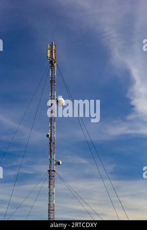Torre di telecomunicazione per telefono cellulare con antenne su un cielo blu. Funzione di distribuzione dei telefoni cellulari a contratto. Foto Stock