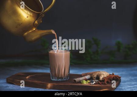 Tè indiano masala chai. Tè speziato Masala chai con latte e spezie o karak chai o taglio chai. Il tè viene versato nei bicchieri da un bollitore Foto Stock