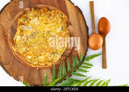 Frittata piccante al peperoncino fatta in casa e pronta da mangiare in un piatto di legno. Frittata all'uovo marrone in piatto di legno e isolato. Omelette speziate preparate in casa in India. Foto Stock