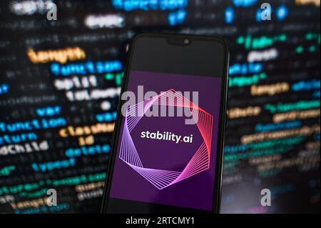 In questa immagine è riportato un logo Stability.ai visualizzato su uno smartphone con codice di programmazione sullo sfondo. Foto Stock