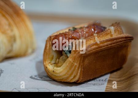 Salsiccia in pasta sfoglia su un piatto di legno, primo piano Foto Stock