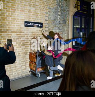 Madre e figlia che hanno la loro fotografia scattata al binario 9 3/4 di Harry Potters, stazione di Kings Cross, Londra Regno Unito Foto Stock