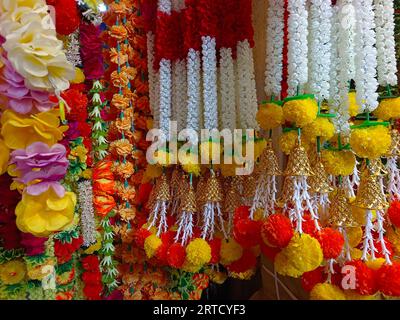 Fiori artificiali multicolori utilizzati per la decorazione del festival Diwali, appesi all'interno di un negozio, il giorno prima del festival Diwali e Ganesh Foto Stock