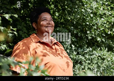 Ritratto di una donna nera anziana che guarda lontano dal verde all'aperto, spazio copia Foto Stock