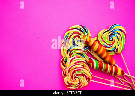 dolci diversi e multicolori, lecca-lecca su sfondo rosa. Copia spazio. Vista dall'alto, concetto di dolci Foto Stock