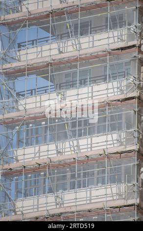 primo piano di ponteggi di costruttori moderni sul lato di un alto edificio, file e linee che formano un modello adatto per lo sfondo o lo sfondo. Foto Stock