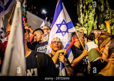 Gerusalemme, Israele. 11 settembre 2023. Un manifestante anti-riforma si trova accanto a una bandiera israeliana durante una manifestazione a Gerusalemme migliaia di manifestanti anti-governativi israeliani si sono radunati fuori dalla Corte Suprema lunedì, alla vigilia di un'audizione storica su un'offerta della coalizione del primo ministro Benjamin Netanyahu di limitare i poteri della corte. Credito: SOPA Images Limited/Alamy Live News Foto Stock