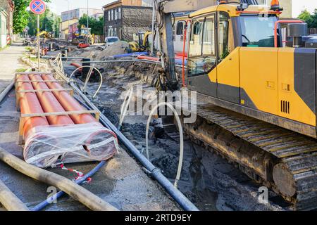 Vista ricostruzione stradale, scavo profondo e ampio, tubi e pozzi sostituiti, nuovi tubi, escavatore Foto Stock