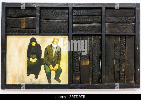 Opere d'arte miste del Simon Janashia National Museum, Tbilisi: Un dipinto realistico raffigura una coppia anziana - una donna con un velo nero e un uomo con una barba bianca, entrambi seduti con le mani agganciate - all'interno di una cornice di grandi dimensioni fatta di travi di legno carbonizzate. Il materiale bruciato può essere interpretato come un riferimento alla guerra, alla perdita e alla memoria collettiva. Shota Rustaveli Avenue, Garetubani, Sololaki, distretto di Mtatsminda, Tbilisi, 0108, Georgia Foto Stock