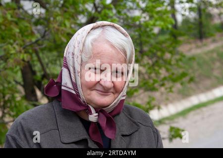 donna anziana con sciarpa e capelli bianchi tipica nonna nelle zone rurali dell'europa orientale Foto Stock