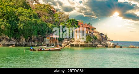 Bungalow fotografati dal traghetto sulla costa di Ko Tao, Thailandia, nascosti tra palme e rocce e posti a gradini verso l'oceano. Foto Stock