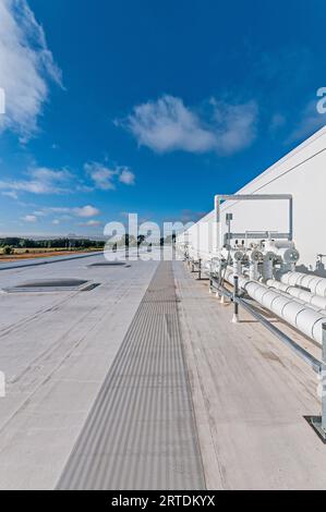 Tubazioni isolate bianche montate sul tetto di un impianto di stoccaggio a freddo, per il trasporto di liquidi e gas nella refrigerazione a ciclo di ammoniaca. Foto Stock