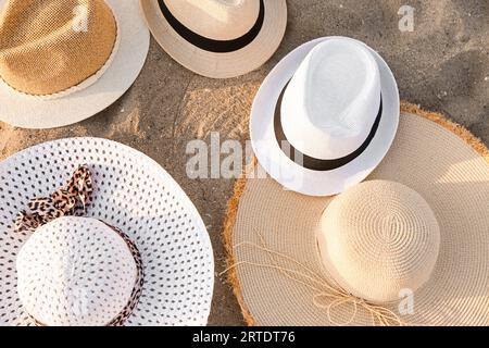 Set di eleganti cappelli di paglia sulla sabbia, primo piano Foto Stock