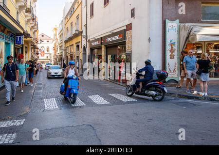 La stretta via Luigi de Maio che ha solo un marciapiede su un lato. L'incrocio conduce a via S Cesareo, una stretta stradina fiancheggiata da negozi turistici nel cuore di Sorrento. Sorrento è una città costiera dell'Italia sud-occidentale, affacciata sul Golfo di Napoli, sulla penisola sorrentina. Arroccato sulla cima di scogliere che separano la città dai suoi affollati porticcioli, è noto per le ampie viste sull'acqua e Piazza tasso, una piazza alberata da caffetterie. Foto Stock