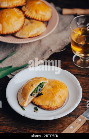 Pasticceria al forno con erba cipollina e funghi blu su piatto bianco e bicchiere di vino Foto Stock