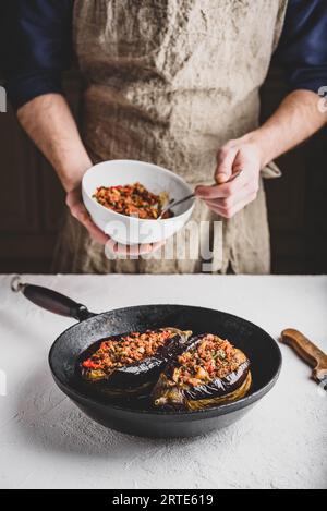 Preparazione delle melanzane farcite con carne macinata, pomodori e spezie. Piatto tradizionale Karniyarik di cucina turca Foto Stock