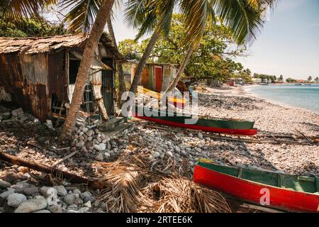 Capanne da pesca e tradizionali barche da pesca scavate lungo la riva del villaggio di Scotts Head nella baia di Soufriere sull'isola di Dominica Foto Stock