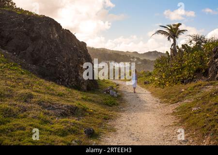 Vista panoramica di una donna che cammina su un sentiero sul mare a Bathsheba; Bathsheba, Barbados, Caraibi Foto Stock