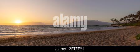 Vista dell'Oceano Pacifico e del sole dorato al crepuscolo dalla spiaggia sabbiosa di Keawakapu Beach; Kihei, Wailea, Maui, Hawaii, Stati Uniti d'America Foto Stock