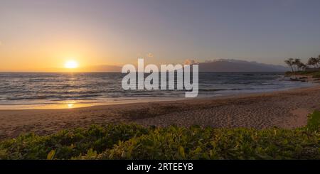 View of Pacific Ocean and golden sun at twilight from the sandy shore of Keawakapu Beach; Kihei, Wailea, Maui, Hawaii, United States of America Stock Photo