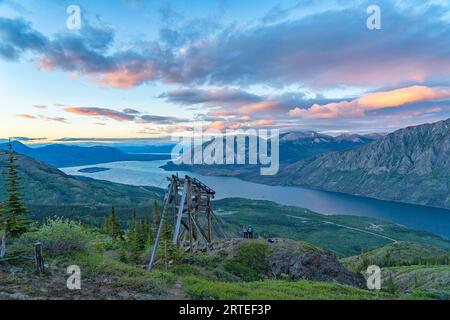 Due donne in piedi su una cima di una montagna accanto a una reliquia mineraria sul Montana Mountain, godendosi il panorama mentre esplorano e fotografano l'incredibile... Foto Stock