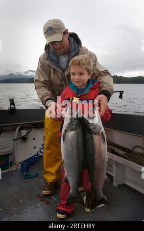 Uomo e ragazzo con salmone d'argento catturato (Oncorhynchus kisutch) a Thorne Bay; Alaska, Stati Uniti d'America Foto Stock