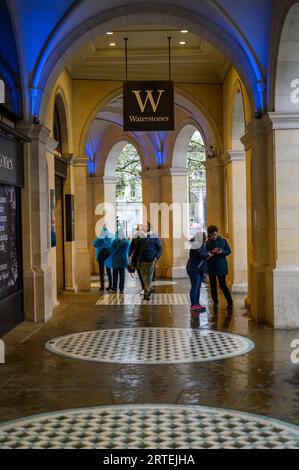 LONDRA - 24 aprile 2023: Scopri il fascino di Londra mentre gli acquirenti trovano rifugio dalla pioggia sotto gli archi storici della libreria Waterstones. Foto Stock
