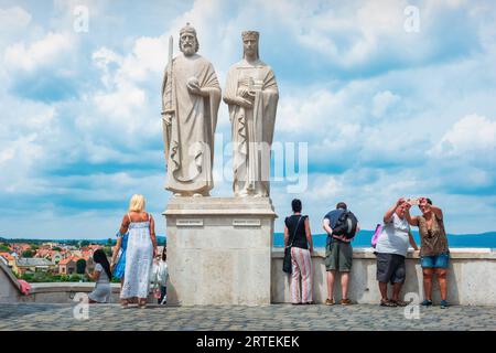 La gente si trova sulle mura del castello di Veszprem accanto alle statue del re Santo Stefano e della regina Gisella nel centro di Veszprém, Ungheria. Foto Stock