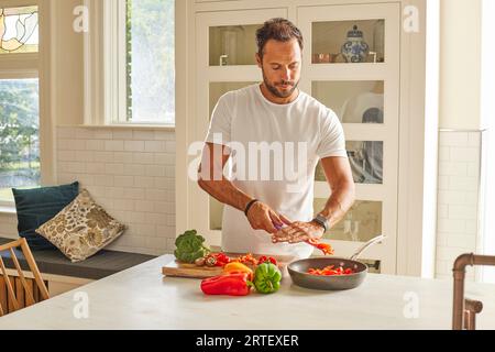 L uomo come tagliare le verdure in cucina Foto Stock