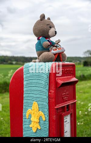 Orsetto all'uncinetto e simbolo scout su una cassetta postale reale del Regno Unito Foto Stock