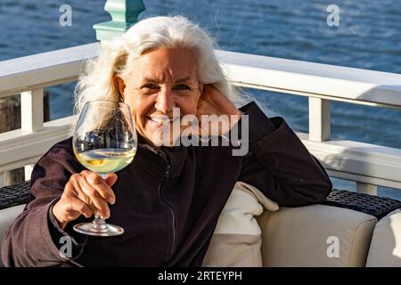Ritratto di una donna anziana sorridente che si rilassa con un bicchiere di vino Foto Stock