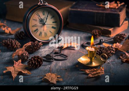 Natura morta d'epoca con libri antichi, orologio e candela. Halloween e concetto occulto. Foto Stock