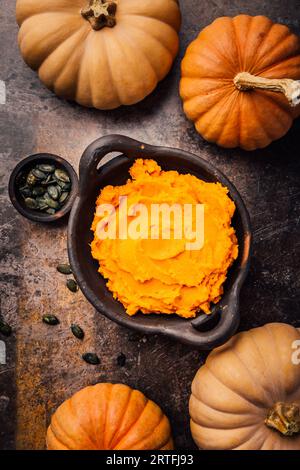 Purè di zucca all'arancia biologica. Zucca di zucca cotta al forno nel recipiente Foto Stock