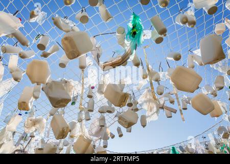 Contenitori di plastica nella rete da pesca contro il cielo blu - concetto di spazzatura, inquinamento idrico, problema ambientale Foto Stock