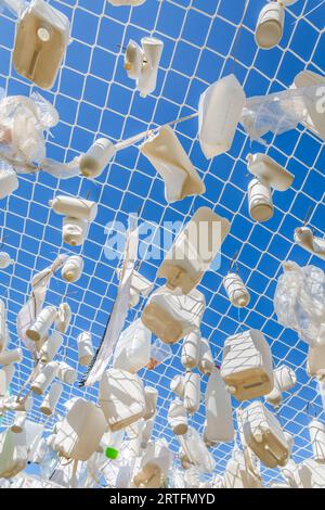 Contenitori di plastica nella rete da pesca contro il cielo blu - concetto di spazzatura, inquinamento idrico, problema ambientale Foto Stock