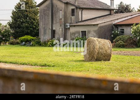 Rustica casa di campagna che mostra una grande balla di fieno sul davanti, a simboleggiare la vita rurale. Foto Stock