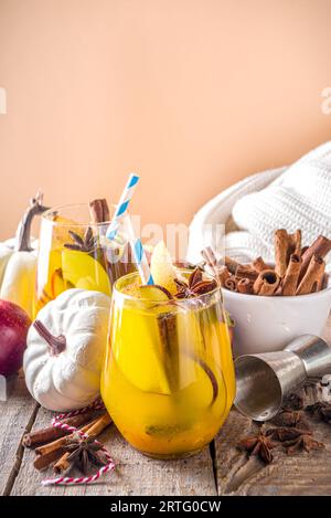 Boozy Pumpkin Party Punch, sangria di ringraziamento con succo di zucca, mela, pera e spezie, fondo in legno accogliente con maglione caldo e ingredienti c Foto Stock