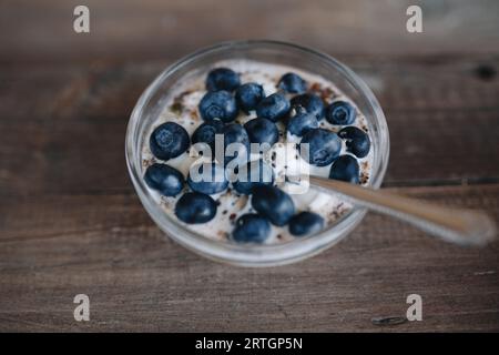 Da sopra ciotola di dessert estivo condita con mirtilli e. semi di chia su tavola di legno Foto Stock