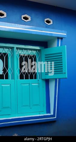 le antiche finestre sono di colore verde brillante con pareti blu Foto Stock