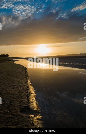 Tramonto a Traeth Bach con cielo blu e mare calmo. Foto Stock