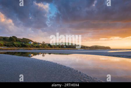 Tramonto a Traeth Bach con cielo blu e mare calmo. Foto Stock