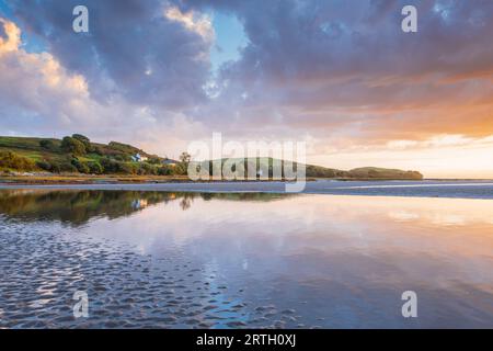 Tramonto a Traeth Bach con cielo blu e mare calmo. Foto Stock