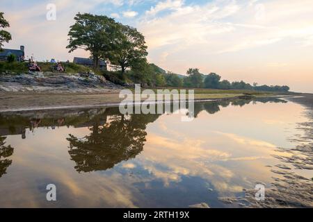 Tramonto a Traeth Bach con cielo blu e mare calmo. Foto Stock