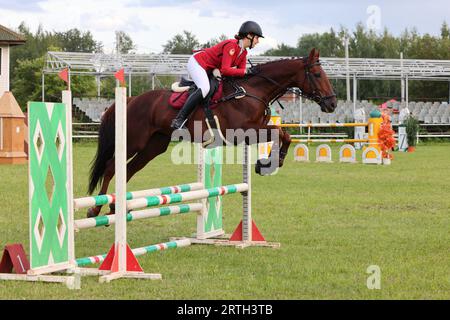 Ragazza in uniforme equestre che salta a cavallo a lehurdle Foto Stock