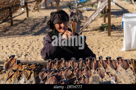 Nazare, Portogallo - 09.12.2022: Anziana signora in nero vende pesce secco Foto Stock