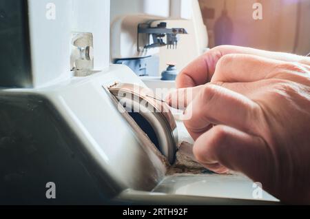 Un uomo affina un ago metallico su una mola. Primo piano della mano maestra Foto Stock